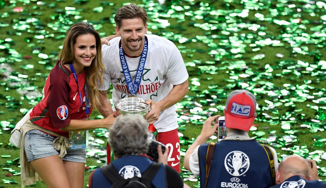 Adrien Silva dan kekasihnya Margarida Neuparth berfoto bersama trofi juara usai mengalahkan Prancis pada final Piala Eropa 2016 di  Stade de France, Saint-Denis, Prancis, (10/7/2016). (AFP/ Miguel Medina)