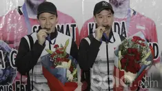 Pebulutangkis ganda putra Indonesia, Kevin Sanjaya/Marcus Gideon, menggigit medali saat tiba di Bandara Soekarno Hatta, Banten, Selasa (14/3/2017). Pasangan ini kembali setelah berhasil meraih gelar All England. (Bola.com/M Iqbal Ichsan)
