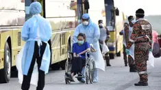 Petugas membawa warga Malaysia menggunakan kursi roda saat tiba setelah dievakuasi dari Wuhan, China akibat virus corona di Bandara Internasional Kuala Lumpur di Sepang, Selasa, (4/2/2020). Sejumlah 107 warga Malaysia dievakuasi Wuhan, China. (Muzzafar Kasim/Malaysia's Ministry of Health/AFP)