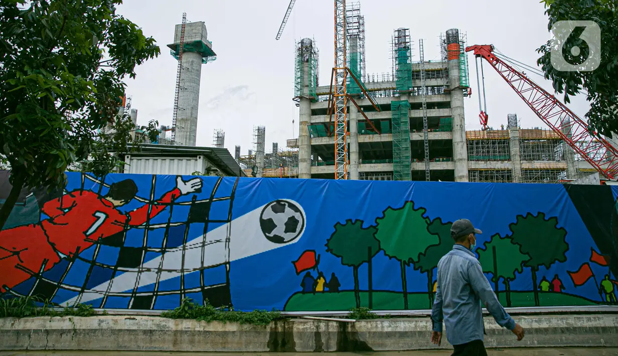 Seorang pria berjalan dekat proyek pembangunan Jakarta International Stadium atau Stadion BMW di kawasan Papanggo, Tanjung Priok, Jakarta, Senin (18/1/2021). Progres pembangunan Jakarta International Stadium atau Stadion BMW ditargetkan rampung pada Oktober 2021. (Liputan6.com/Faizal Fanani)