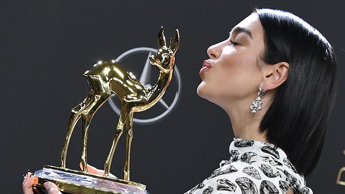 Penyanyi Inggris Dua Lipa  mencium Penghargaan Bambi Awards ke-70 yang ia raih di Potsdamer Platz di Berlin (16/11). Dua Lipa meraih penghargaan kategori Music International di acara tersebut. (AFP Photo/Jens Kalaene)