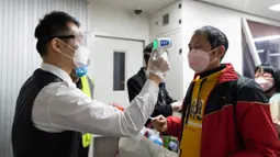 Seorang staf mengukur suhu tubuh penumpang  di Bandara Liuji di Kota Xiangyang, Provinsi Hubei, China (29/3/2020). Layanan penerbangan penumpang domestik kembali beroperasi di Hubei, wilayah yang sempat terdampak COVID-19, kecuali layanan di Bandara Internasional Tianhe Wuhan. (Xinhua/Xie Jianfei)