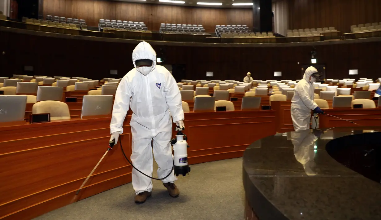 Pekerja dari Asosiasi Pengendalian Hama Korea menyemprotkan disinfektan di Majelis Nasional Seoul (25/2/2020). Pihak berwenang melaporkan 169 infeksi baru. Termasuk di antaranya seorang tentara AS, sehingga jumlah keseluruhannya menjadi 1.146. (AFP/Yonhap)