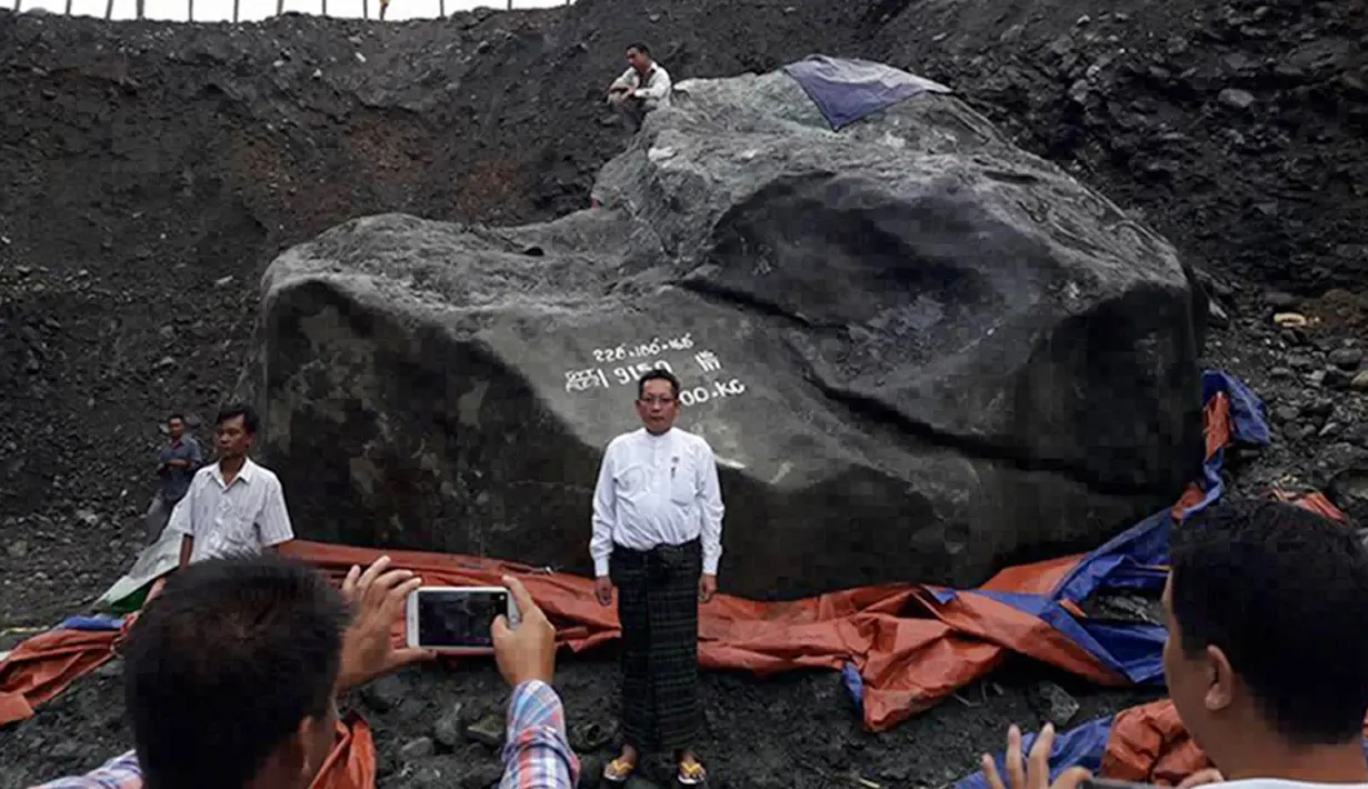 Pejabat setempat, Tint Soe berpose di samping batu giok yang ditemukan penambang di lokasi tambang di negara bagian Kachin, Myanmar, Kamis (20/10). Perusahaan yang menemukan batu giok itu masih belum memutuskan giok itu akan digunakan jadi apa. (STR/AFP)