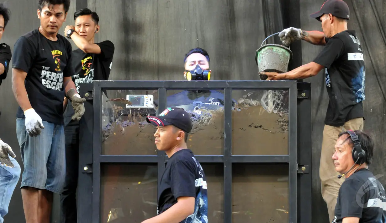 Sejumlah kru tampak menumpahkan semen ke tubuh Demian, Jakarta, Jumat (22/5/2015). Tampak Demian mengenakan masker saat proses penimbunan dirinya. (Liputan6.com/Panji Diksana) 