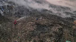 Petugas pemadam kebakaran berusaha memadamkan api di Tempat Pembuangan Akhir (TPA) Jatiwaringin, Kabupaten Tangerang, Banten, Jumat (03/07/2026). (Merdeka.com/ Arie Basuki)