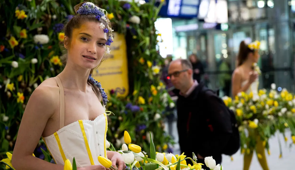 Model tersenyum saat mengenakan gaun berhiaskan bunga-bunga saat berlangsungnya pameran bunga Keukenhof di Central Station di Utrecht, Belanda, (29/3). Pameran ini menghadirkan sekitar 20.000 bunga musim semi. (AP Photo / Peter Dejong)