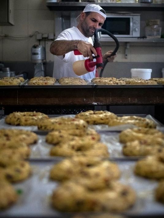 Seorang tukang roti membuat Bolo Rei atau Kue Raja di toko roti Padaria da Ne, Amadora, Portugal, 16 Desember 2022. Bolo Rei terdiri dari kacang kismis, buah-buahan, dan lapisan gula. (CARLOS COSTA/AFP)