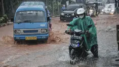 Pengendara mendorong sepeda motor saat melintasi genangan lumpur di Jalan Raya Sawangan, Depok, Minggu (7/11/2021). Hujan deras yang mengguyur Depok dan sekitarnya menyebabkan Jalan Raya Sawangan  digenangi banjir lumpur dan membahyakan keselamatan pengendara. (merdeka.com/Iqbal S Nugroho)