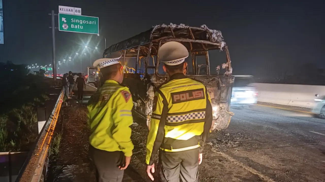 Petugas berjaga di depan minibus jenis Elf yang hangus terbakar di Tol Pandaan-Malang pada Jumat, 26 September 2025 petang