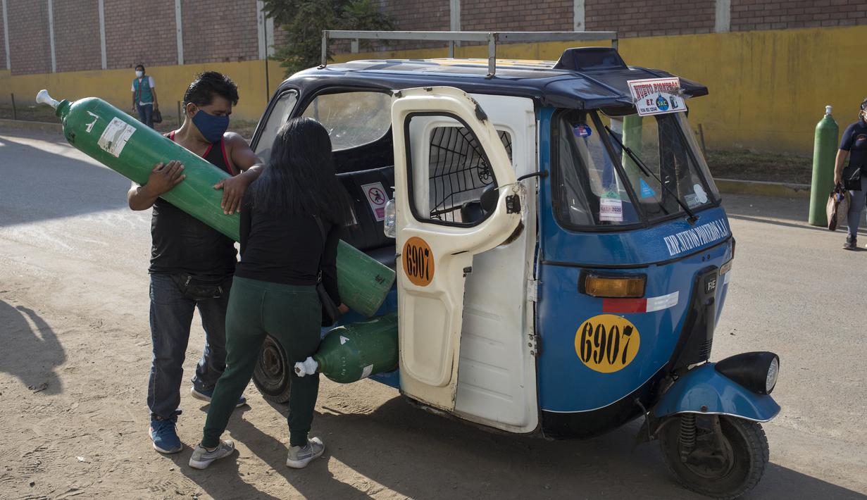 Sepasang suami istri memuat tangki oksigen yang baru diisi ke dalam ojek untuk orang tercinta yang terinfeksi COVID-19 di Villa El Salvador, Lima, Peru, Selasa (6/4/2021). Warga Peru terus berjuang mendapatkan oksigen medis untuk merawat pasien COVID-19. (AP Photo/Rodrigo Abd)