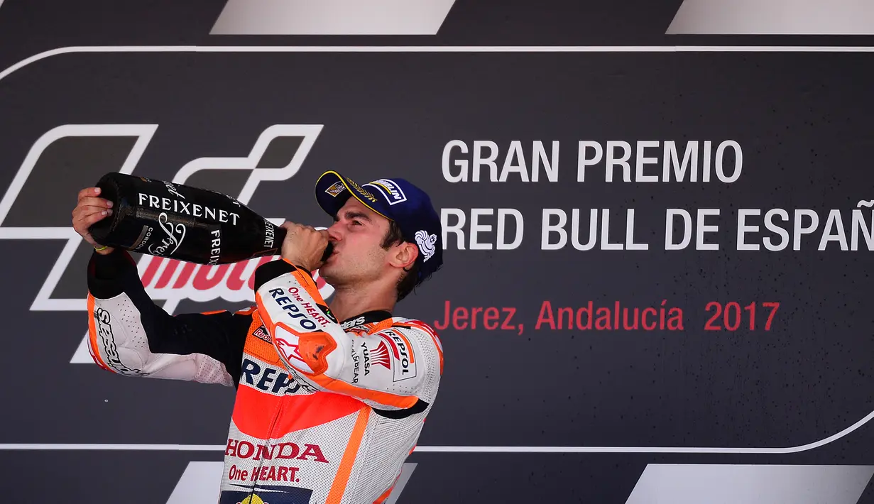 Pembalap Repsol Honda, Dani Pedrosa meminum sampanye untuk merayakan kemenangannya pada balapan MotoGP Spanyol di Sirkuit Jerez, Minggu (7/5). Kemenangan itu merupakan yang ke-53 kalinya sejak mengikuti Grand Prix. (CRISTINA QUICLER / AFP)