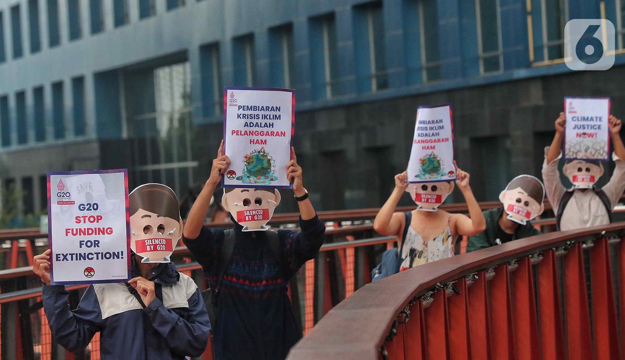 Sejumlah aktivis yang tergabung dalam Extintion Rebellion (XR) dan Walhi Jakarta melakukan aksi di JPO Pinisi, Jalan Jenderal Sudirman, Jakarta, Senin (14/11/2022). Aksi tersebut dilakukan untuk menyerukan kepada para pemimpin agar menghentikan “pencucian hijau” dan praktik ekonomi “business-as-usual” yang secara sistematis memperburuk krisis iklim dan mendorong umat manusia pada kehancuran ekologis & kepunahan massal. Negara-negara G20 turut menyumbang atas 80 persen emisi karbon dunia dan 60 persen populasi penduduk bumi. (Liputan6.com/Angga Yuniar)