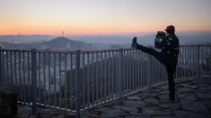 Seorang pejalan kaki mengabadikan kota Seoul dan menara Namsan dengan ponselnya selama matahari terbit di Korea Selatan (31/10). Seoul adalah ibu kota Korea Selatan yang berusia lebih dari 600 tahun. (AFP Photo/Ed Jones)