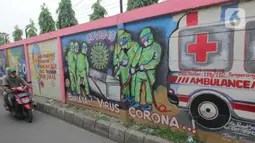 Pemotor melintasi mural bertema covid-19 di Tanah Tinggi, Tangerang, Sabtu (29/1/2022). Kasus Covid-19 varian Omicron di Indonesia terus bertambah dan wilayah penyebarannya semakin meluas. Diperkirakan, kasus omicron sudah mendominasi penularan virus corona di Jawa Bali. (Liputan6.com/Angga Yuniar)