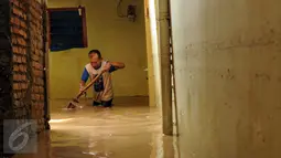 Seorang warga membersihkan sisa lumpur di Rawajati, Kalibata, Jakarta, Senin (16/11/2015).Hujan deras yang melanda Bogor, Minggu (15/11) mengakibatkan puluhan rumah warga di bantaran sungai Ciliwung terendam. (Liputan6.com/Helmi Fithriansyah)