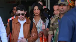 Aktris India Priyanka Chopra (tengah) dan musisi AS Nick Jonas (kiri) tiba di Jodhpur, Rajasthan, India, Kamis (29/11). Berdasarkan laporan India Today, Chopra dan Nick bakal menggelar ritual berjoget ala Bollywood. (AP Photo/Sunil Verma)