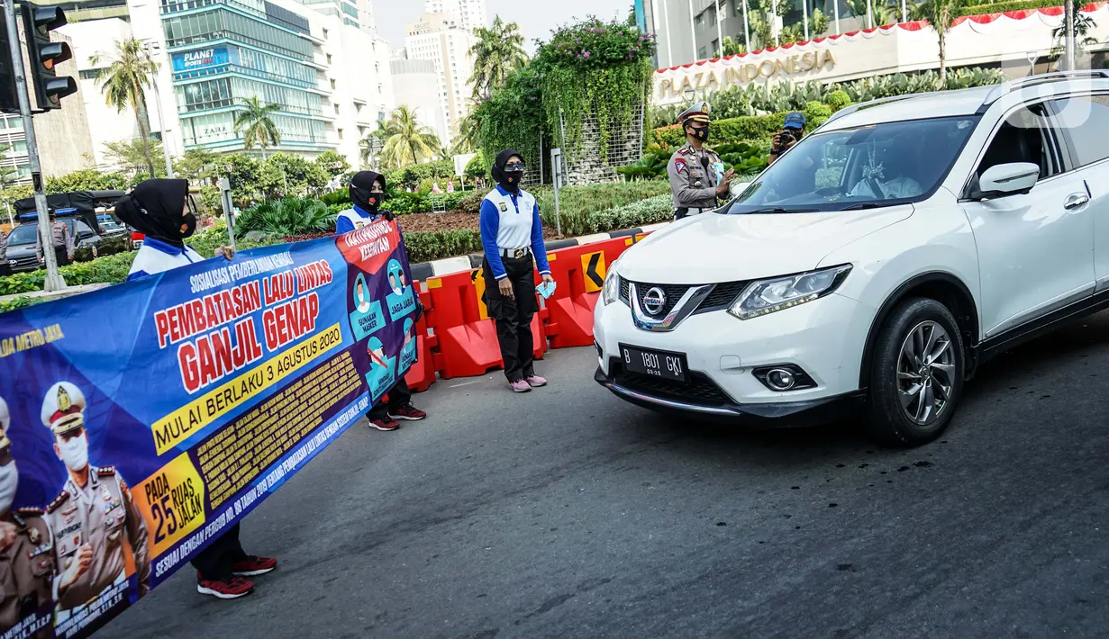 Petugas kepolisian membentangkan spanduk saat sosialisasi pelaksanaan ganjil genap di Kawasan Bundaran HI, Jakarta, Minggu (2/8/2020). Ditlantas Polda Metro Jaya kembali memberlakukan sistem ganjil genap di 25 ruas jalan protokol  DKI Jakarta mulai Senin, 3 Agustus 2020. (Liputan6.com/Faizal Fanani)