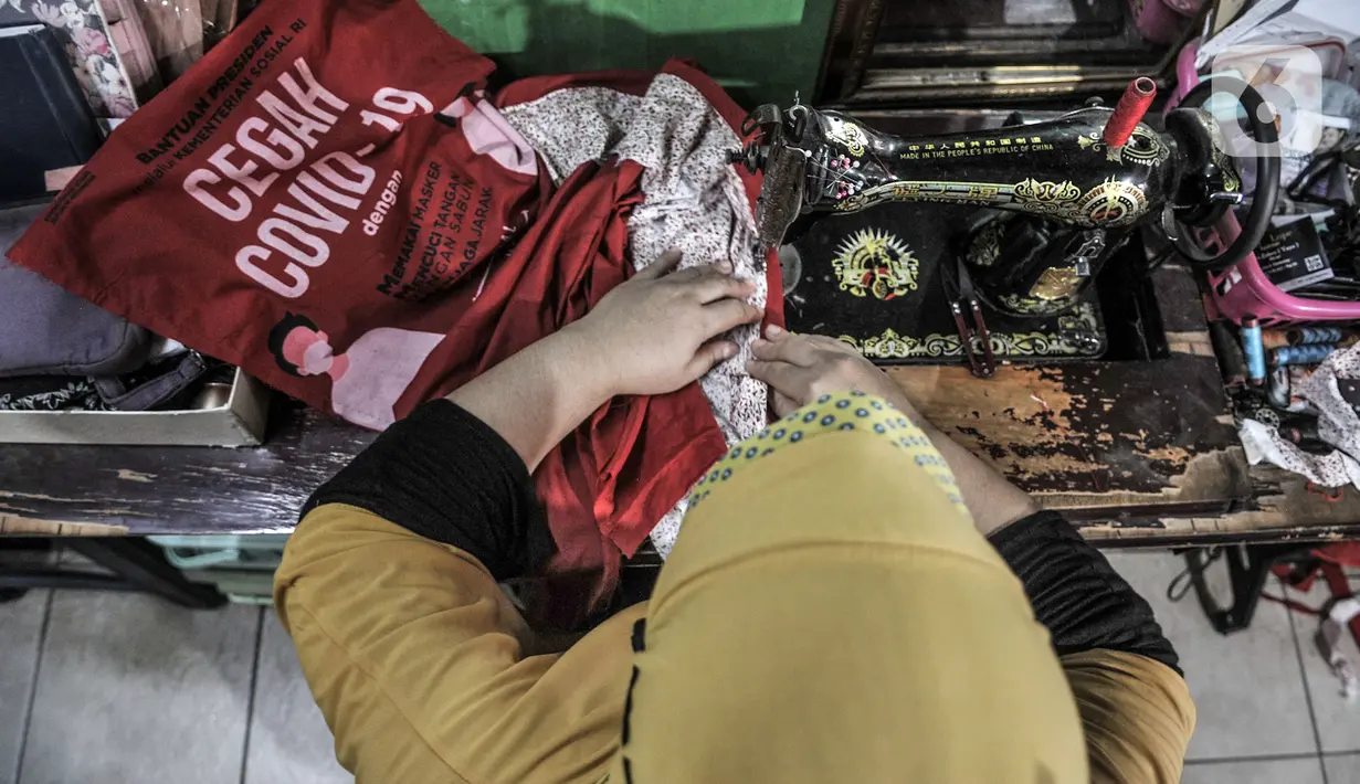 Siti Zahro (44) menyelesaikan pembuatan celemek berbahan tas bansos Covid-19 di industri jahit rumahan KG-Lupe Fashion, Salemba, Jakarta, Senin (16/11/2020). Siti berinovasi membuat celemek berbahan tas bansos Covid-19 yang didapat dari pemerintah selama PSBB. (merdeka.com/Iqbal S. Nugroho)
