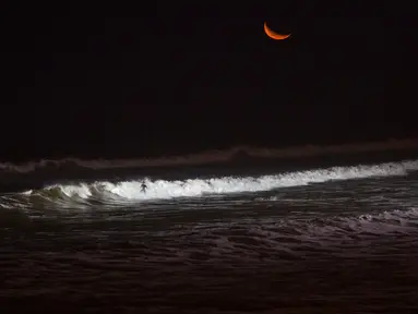 Seorang wisatawan meluncur ke dalam gulungan ombak saat berselancar di pantai La Pampilla, ibu kota Peru, Lima, 2 Maret 2017. Sekelompok peselancar hardcore memilih bermain selancar pada malam hari. (AP Photo/Rodrigo Abd)