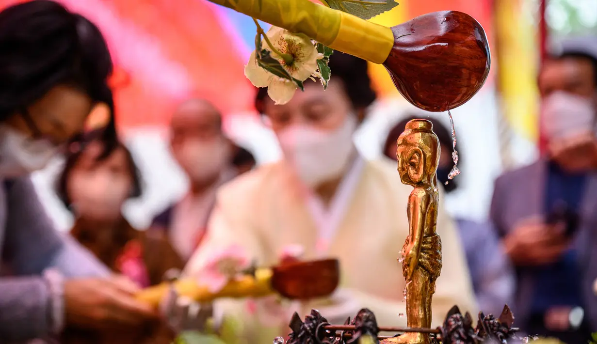 <p>Jemaah mencuci patung Buddha saat kebaktian untuk merayakan ulang tahun Buddha di Kuil Jogye, Seoul, Korea Selatan, Minggu (8/5/2022). (ANTHONY WALLACE/AFP)</p>