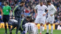 Bomber Real Madrid, Gareth Bale (duduk), saat mendapat perawatan medis karena mengalami cedera ketika menghadapi Sporting Gijon, pada laga lanjutan La Liga, di Santiago Bernabeu, Minggu (17/1/2016). (Daily Mail)