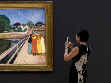 Pengunjung mengabadikan lukisan karya seniman Norwegia, Edvard Munch “Girls on the Bridge” di New York, 4 November 2016. Dalam sebuah lelang pada 14 November, lukisan dari 1902 itu terjual dengan harga USD54,5 juta (setara Rp727 M). (Timothy A. CLARY/AFP)