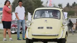 Seorang pria mengendarai mobil model BMW Isetta kuning klasik selama pertemuan klasik Kairo ke-7 di Kairo, Mesir (23/3). Pertemuan ini menjadi ajang nostalgia bagi para pecinta mobil klasik. (Reuters/Mohamed Abd El Ghany)