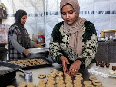 Para wanita menyiapkan biskuit tradisional "kaak" yang berbentuk cincin menjelang Idul Fitri, hari raya yang menandai berakhirnya bulan puasa suci Ramadan, di Kota Gaza pada 16 Maret 2026. (Omar AL-QATTAA/AFP)