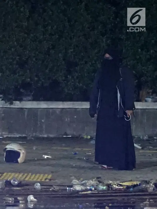 Seorang perempuan bercadar hitam dengan kabel menjuntai di tangan berusaha mendekat Gedung Bawaslu, Jakarta, Rabu (22/5/2019). Perempuan misterius yang berjalan sendiri tanpa massa ini mengenakan baju gamis warna hitam. (Liputan6.com/Immanuel Antonius)