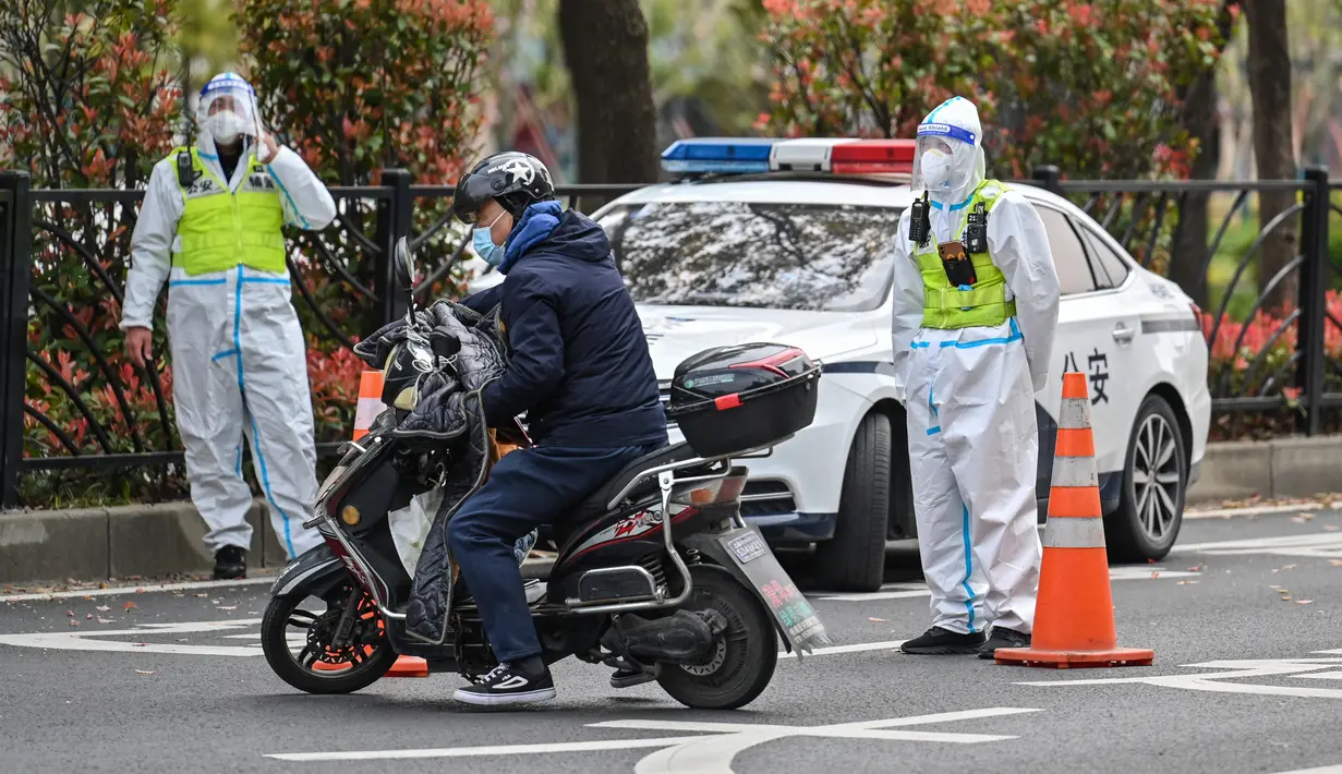 Petugas polisi yang mengenakan alat pelindung mengontrol akses ke terowongan ke arah distrik Pudong yang dikunci sebagai tindakan melawan virus corona Covid-19, di Shanghai (28/3/2022). (AFP/Hector Retamal)