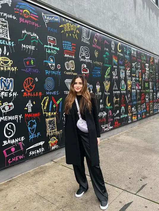 Yasmine Wildblood juga tampak masih betah meghabiskan waktu bersama keluarganya di luar negeri. Terlihat di foto ini, Yasmine berpose dengan latar tembok yang digambari dengan mengenakan sweater, ditumpuk dengan long coat, dan dipadu dengan celana panjang hitam, serta sneakers yang semuanya berwarna hitam. Ia juga tampak membawa sling bag berwarna silver. Foto: Instagram.