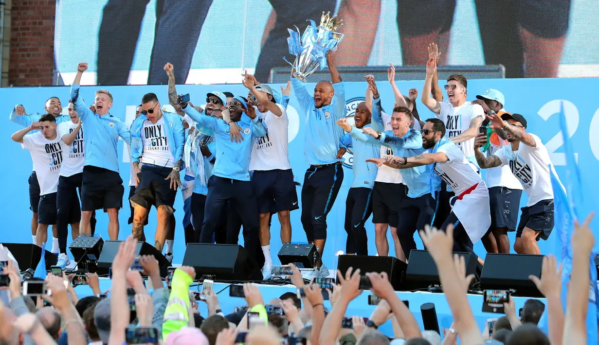 Pemain Manchester City mengangkat trofi Liga Primer Inggris selama melakukan parade merayakan keberhasilan menjadi juara Liga Primer Inggris di Manchester, Senin (14/5). Manchester City menjuarai Liga Inggris ke-18 kalinya.  (Richard Sellers/PA via AP)