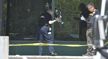 Seorang teknisi Polisi Metro Louisville memotret lubang peluru pada kaca depan Gedung Old National Bank di Louisville, Kentucky, Amerika Serikat, Senin (10/4/2023). (AP Photo/Timothy D. Easley)