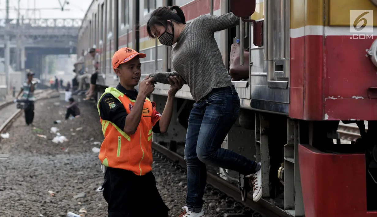Petugas membantu penumpang turun dari KRL Commuter Line saat kereta berhenti beroperasi di Jatinegara, Jakarta, Minggu (4/8/2019). Listrik padam yang melanda Jakarta dan  sekitarnya mengakibatkan penumpang KRL Commuter Line telantar lantaran kereta berhenti beroperasi. (merdeka.com/Iqbal Nugroho)
