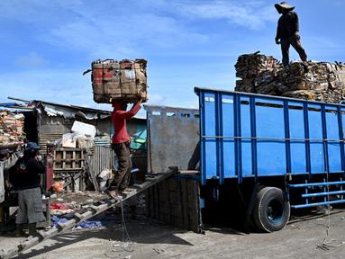 Orang-orang memuat kertas bekas ke truk setelah ditimbang sebelum dijual ke pemulung di Denpasar, Bali, Sabtu (20/1/2024). Pemerintah Kota Denpasar membangun sinergi dengan para pemangku kepentingan terkait untuk mengoptimalkan upaya penanganan sampah di wilayahnya. (SONNY TUMBELAKA/AFP)