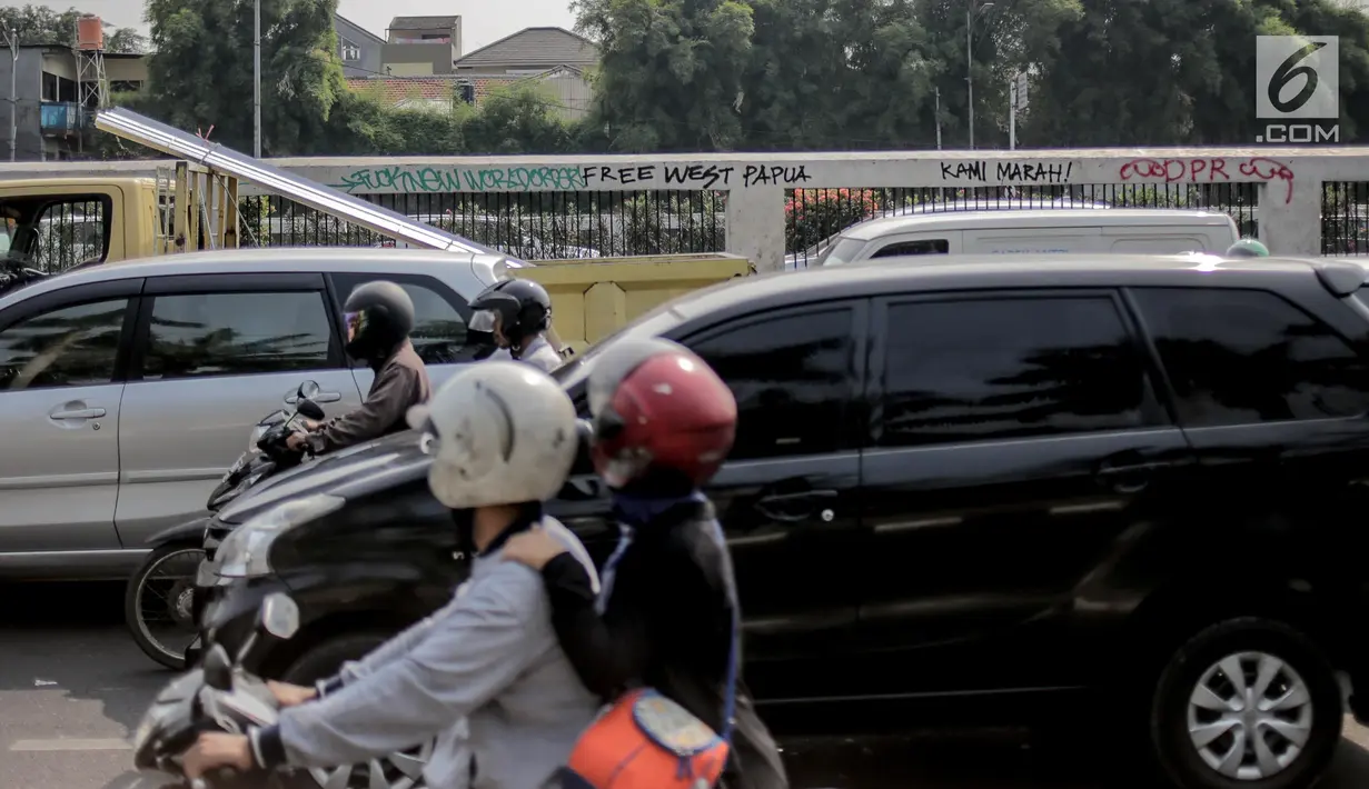 Pengendara melintasi dekat coret-coretan (vandalisme) di sekitar Gedung DPR/MPR RI, Jakarta, Selasa (24/9/2019). Demonstrasi mahasiswa dari berbagai kampus yang menolak pengesahan RUU Kitab Undang-Undang Hukum Pidana(KUHP) tercoreng oleh aksi vandalisme. (Liputan6.com/Faizal Fanani)