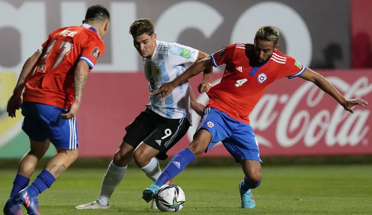 Pemain Argentina Julian Alvarez (tengah) berebut bola dengan dan pemain Chile Mauricio Isla (kanan) pada pertandingan sepak bola Kualifikasi Piala Dunia 2022 di Stadion Zorros del Desierto, Calama, Chile, 27 Januari 2022. Argentina menang 2-1. (Esteban Felix/POOL/AFP)
