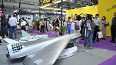 Pengunjung terlihat di samping model drone UAV Flying Eagle H3200 di stan Micro Multi Copter (MMC) selama Drone World Congress (DWC) di Shenzhen pada 21 Mei 2026. (HECTOR RETAMAL/AFP)