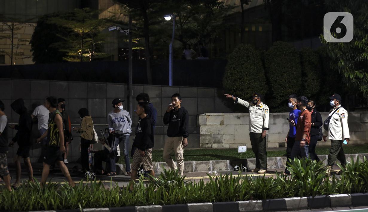 Satpol PP membubarkan kerumunan warga saat perayaan malam Tahun Baru di Jakarta, Jumat (31/12/2021). Polda Metro Jaya melakukan pengendalian mobilitas Crowd Free Night (malam bebas keramaian) dengan membubarkan warga yang nekat keluar rumah dan tidak mematuhi aturan. (Liputan6.com/Johan Tallo)