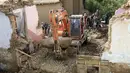 Sebuah ekskavator mengangkat lumpur dan bebatuan dari rumah yang rusak setelah banjir besar di provinsi Maidan Wardak di Afghanistan tengah, Minggu, 23 Juli 2023.  (AP Photo)