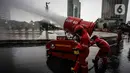 Petugas pemadam kebakaran menyemprotkan cairan disinfektan menggunakan robot LUF 60 di kawasan Bundaran HI, Jakarta, Minggu (22/3/2020). Penyemprotan untuk mencegah penyebaran virus corona COVID-19 ini dilakukan di lima wilayah Ibu Kota. (Liputan6.com/Faizal Fanani)