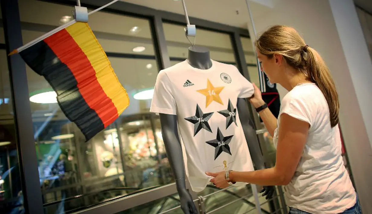 Petugas toko di Frankfurt, (14/7/2014), merapikan kaos berlogo federasi sepak bola Jerman dengan empat bintang. Tanda bintang pada kaos timnas melambangkan jumlah capaian gelar juara di ajang Piala Dunia. (AFP PHOTO/DPA/Fredrik VON Erichsen)