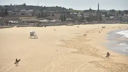 Pantai Bondi yang kosong setelah pemerintah menutup pantai paling populer di Sydney, Minggu (22/3/2020). Otoritas Australia menutup Bondi Beach  lantaran orang-orang mengabaikan larangan pemerintah untuk tidak berkumpul dalam jumlah besar guna menekan penyebaran virus corona. (PETER PARKS/AFP)
