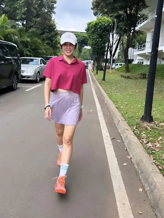 <p>Ussy Sulistiawaty tampil dengan crop top polo sangria, dipadukan skirt orcid. Ia pun mengenakan topi putih dan sneakers orange. (@ussypratama)</p>