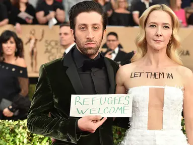 Aktor Simon Helberg dan istri, Jocelyn Towne menarik perhatian di karpet merah Screen Actors Guild (SAG) Awards di Los Angeles, Minggu (29/1). Bintang 'The Big Bang Theory' itu membawa papan bertuliskan 'Refugees Welcome'. (Jordan Strauss/Invision/AP)