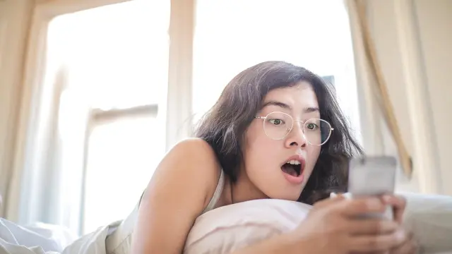 Wanita pakai hp di kasur (pexels)