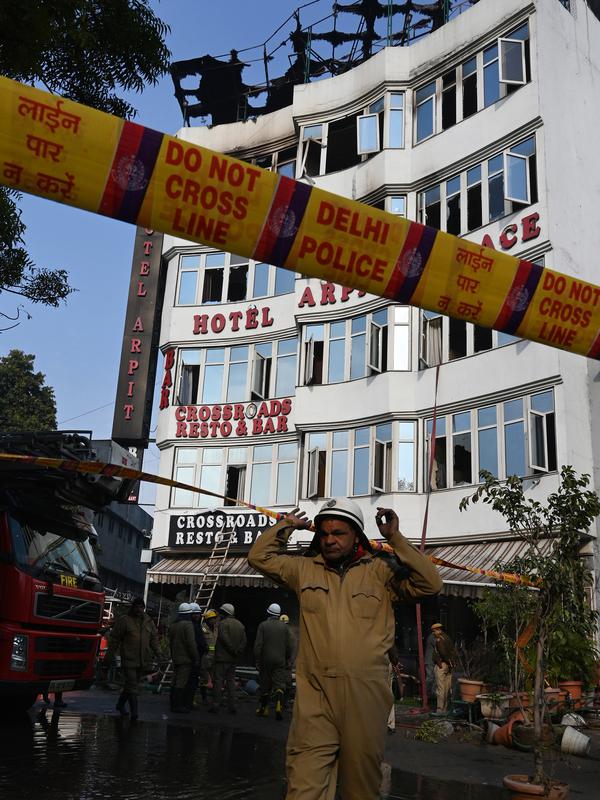 Personel kepolisian berada di luar Hotel Arpit Palace yang terbakar di Distrik Karol Bagh, New Delhi, Selasa (12/2). Sebanyak 20 truk pemadam kebakaran dikerahkan ke lokasi setelah panggilan darurat pada subuh waktu setempat. (Prakash SINGH / AFP)