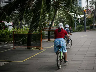 Pengunjung bersepeda di kawasan Taman Impian Jaya Ancol, Jakarta, Sabtu (11/10/2021). Kawasan rekreasi Taman Impian Jaya Ancol menjadi salah satu dari 20 destinasi wisata yang direkomendasikan beroperasi kembali dalam uji coba pembukaan kawasan rekreasi. (Liputan6.com/Faizal Fanani)
