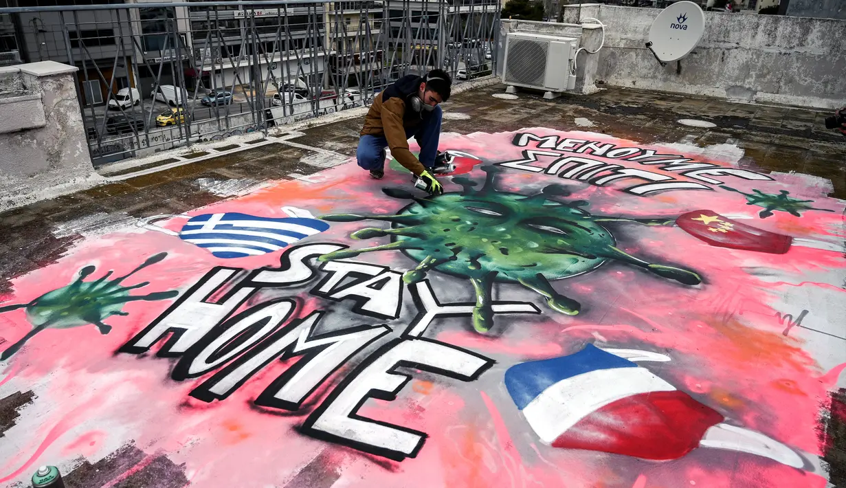 Seniman berusia 16 tahun, S.F. melukis mural tentang pandemi virus corona COVID-19 di atap gedung di Athena, Yunani, Senin (23/3/2020). (Aris Messinis/AFP)